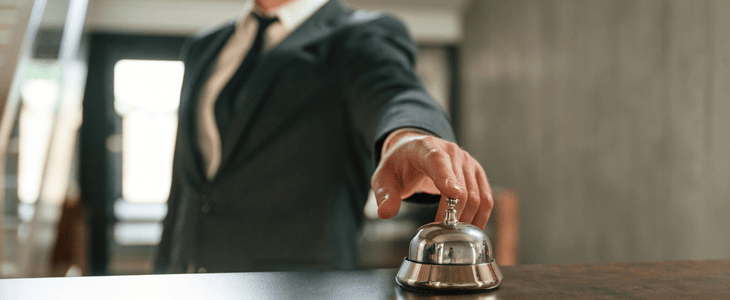 A business man presses bell at hotel lobby
